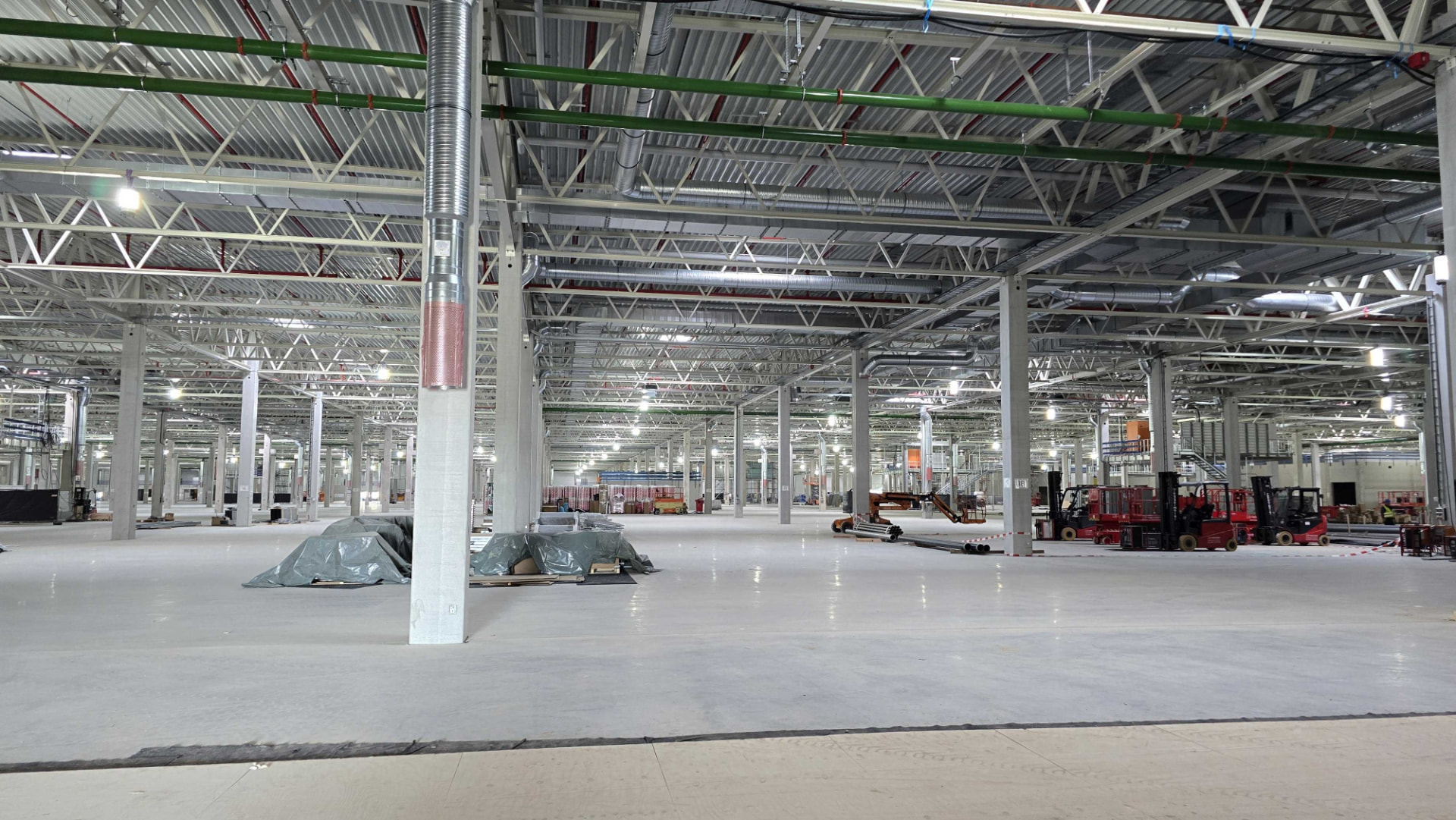 Große Industriehalle im Rohbau mit Lüftungsrohren und Stützen