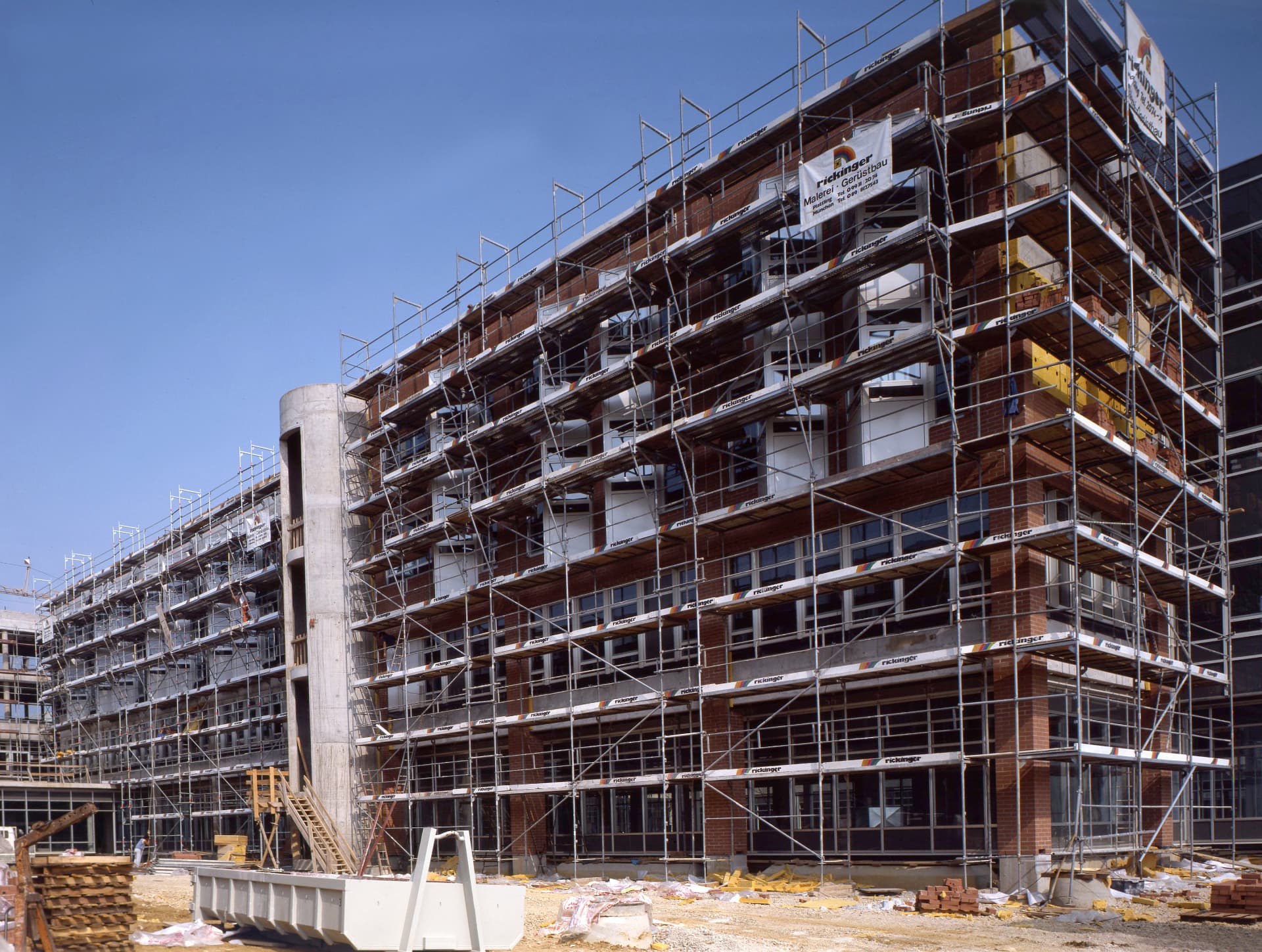 Neubau mit eingerüsteter Fassade und Rickinger-Werbebanner